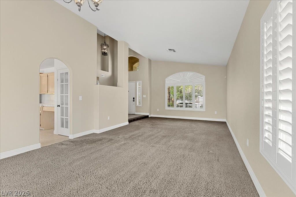 2000 Silverton Drive, Henderson, NV 89074 A generously sized living room boasts carpeted floors and well-lit interiors, with a French door leading to the kitchen.