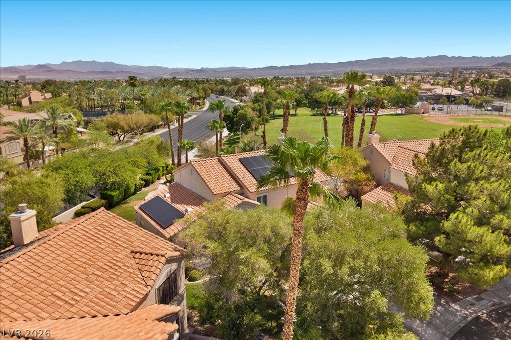 2000 Silverton Drive, Henderson, NV 89074 An aerial perspective reveals a vibrant neighborhood with tile roofs, lush palm trees, and scenic mountain views.