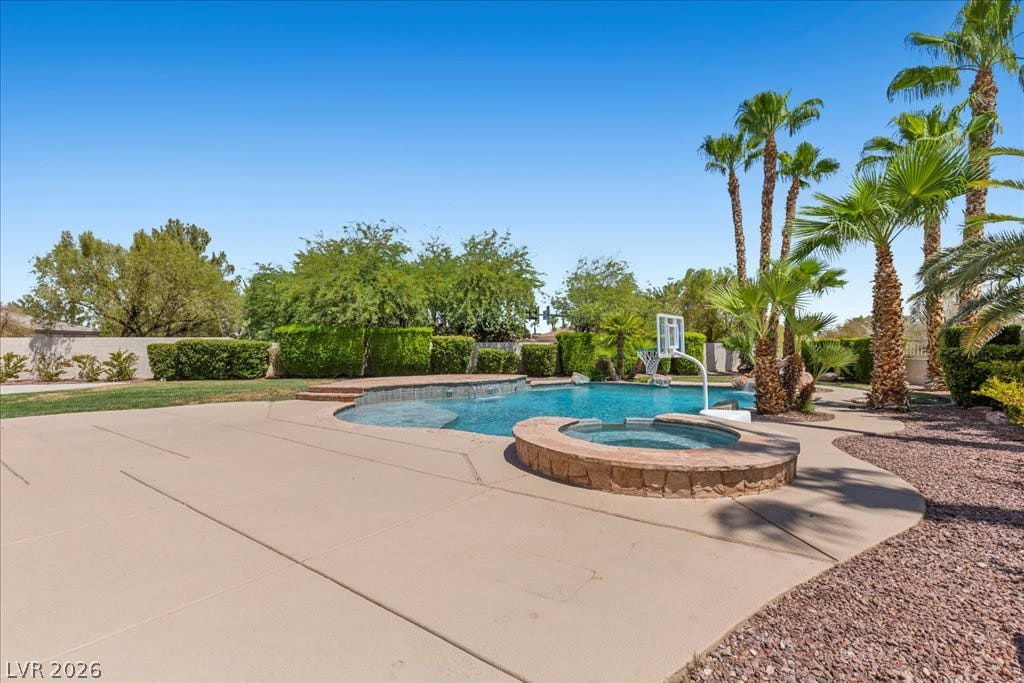 2000 Silverton Drive, Henderson, NV 89074 An inviting backyard oasis offers a sparkling pool and spa, surrounded by lush landscaping and mature palm trees.