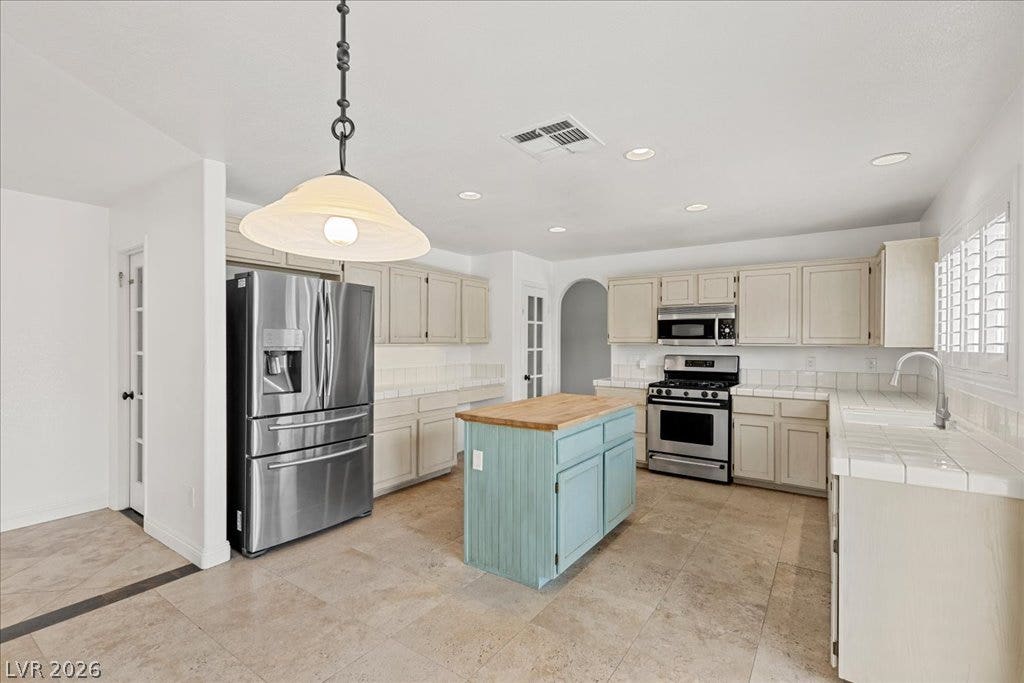 2000 Silverton Drive, Henderson, NV 89074 A well-lit culinary space features an inviting central island and a full suite of stainless steel appliances.