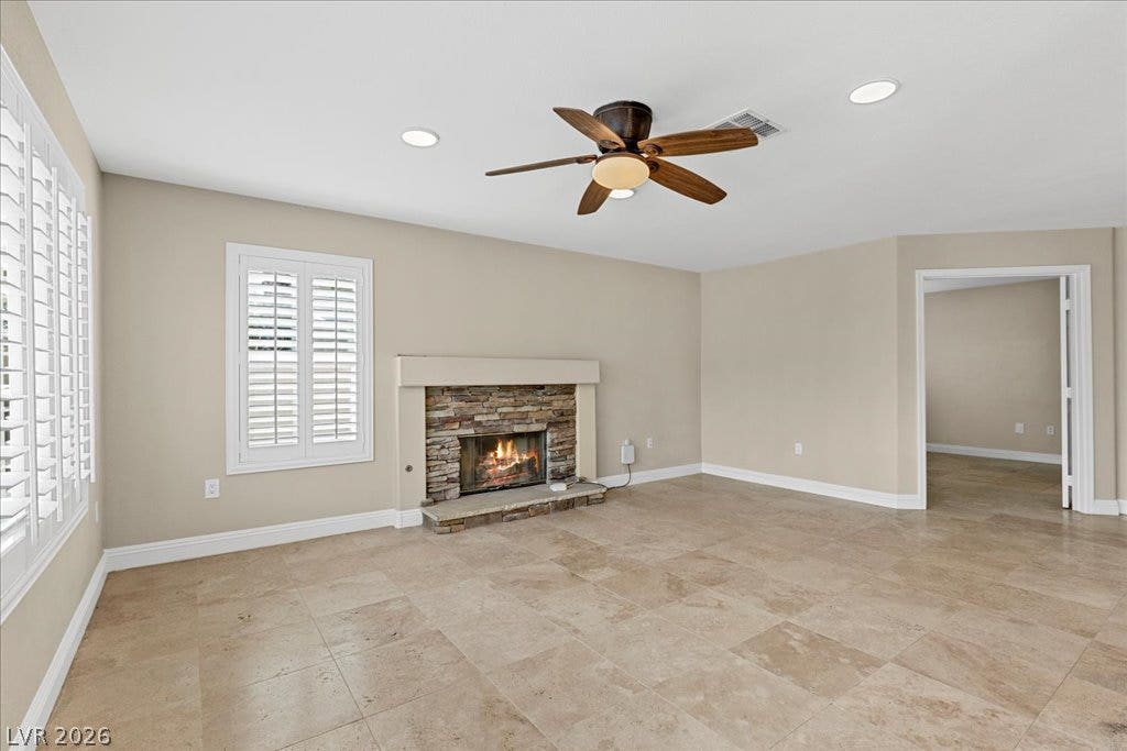 2000 Silverton Drive, Henderson, NV 89074 A comforting living area boasts a stone-clad fireplace and a subtle ceiling fan, creating an inviting atmosphere.