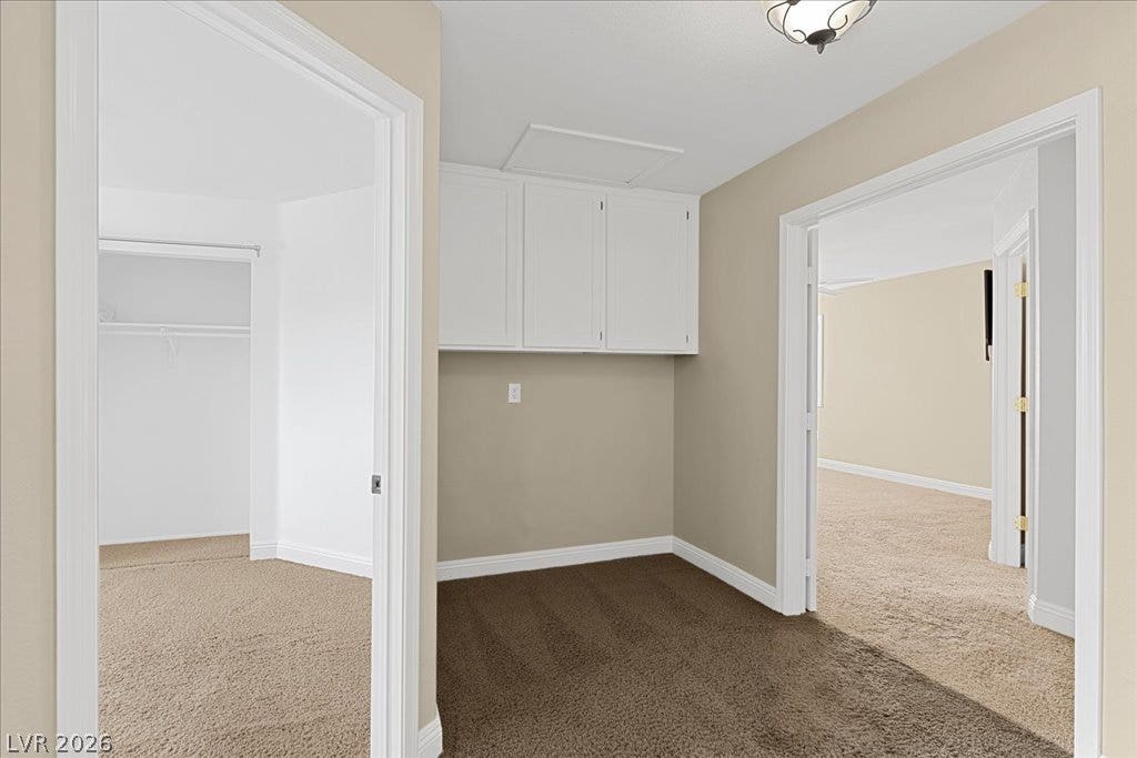 2000 Silverton Drive, Henderson, NV 89074 A well-lit hallway with carpeted floors provides access to multiple rooms, offering ample storage with white cabinetry.