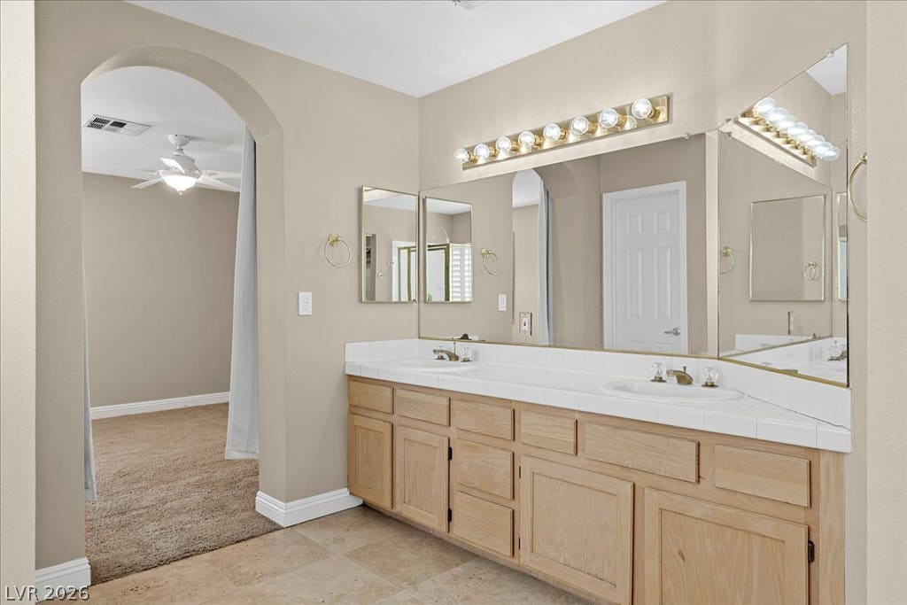 2000 Silverton Drive, Henderson, NV 89074 A well-appointed primary bathroom vanity features dual sinks and ample storage, with an archway leading to the adjoining bedroom.