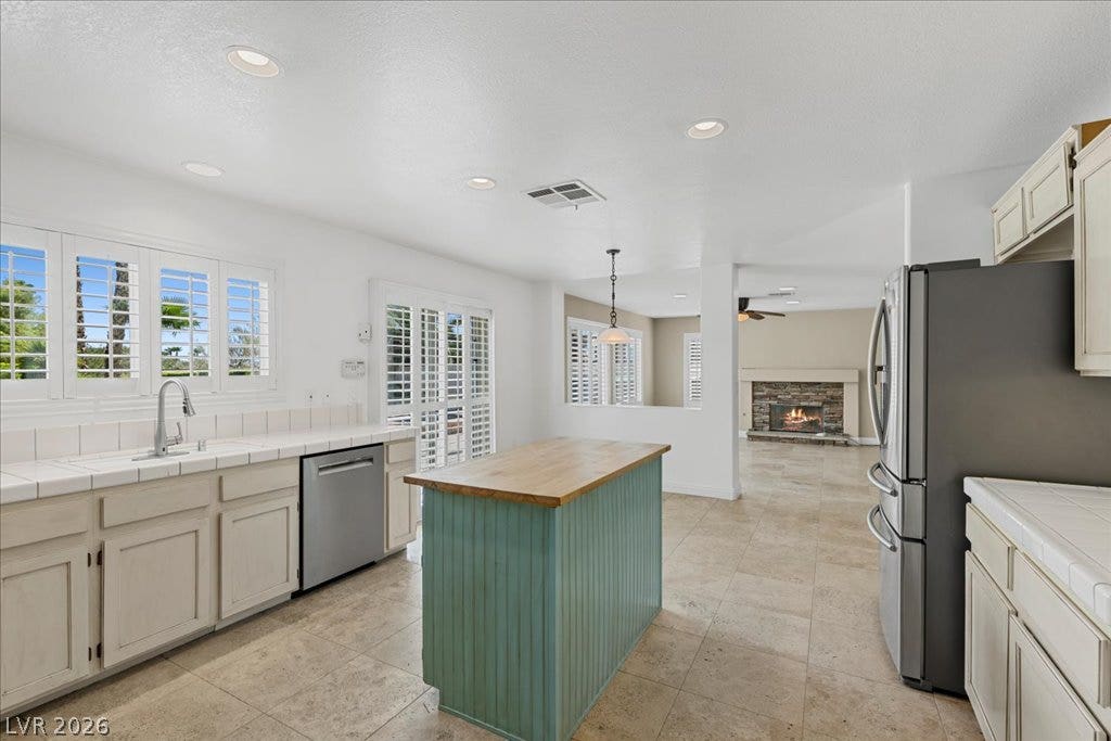 2000 Silverton Drive, Henderson, NV 89074 A well-lit kitchen with a central island and contemporary appliances, seamlessly flows into a living space featuring a fireplace.