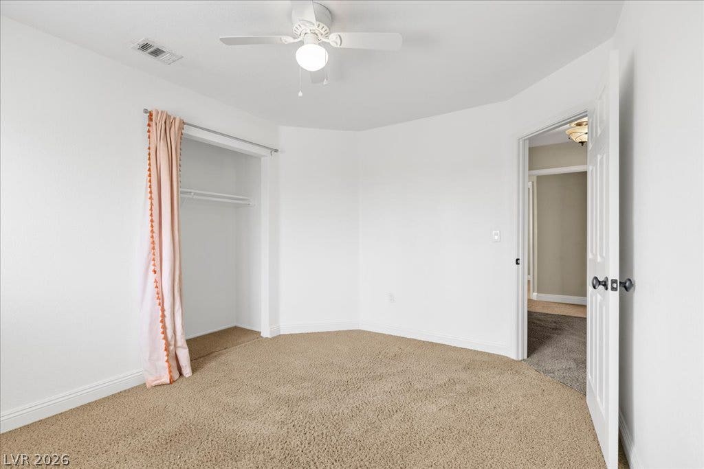 2000 Silverton Drive, Henderson, NV 89074 A well-lit bedroom features plush carpeting and an open closet, complete with a ceiling fan for optimal air circulation.