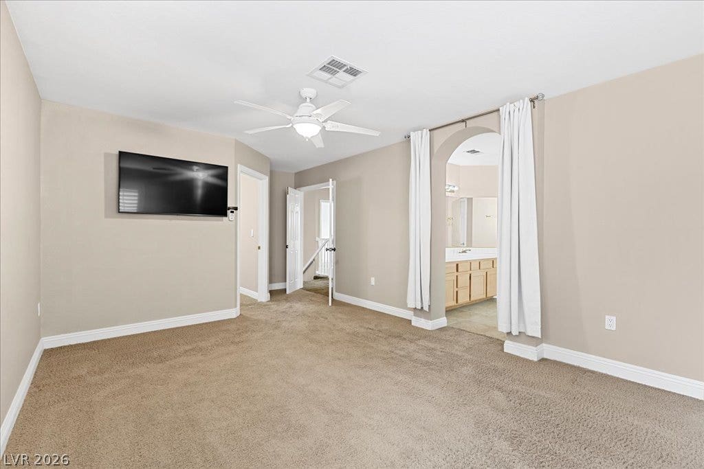 2000 Silverton Drive, Henderson, NV 89074 A spacious primary suite boasts plush carpeting and a convenient ceiling fan for year-round comfort.