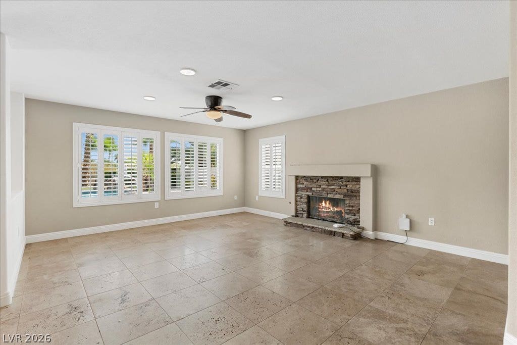 2000 Silverton Drive, Henderson, NV 89074 A welcoming living area boasts a cozy fireplace with a natural stone hearth, complemented by sun-filtering plantation shutters.