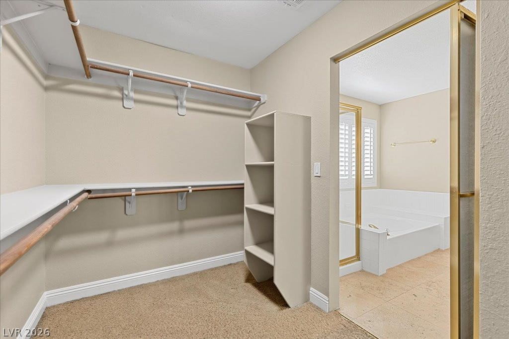 2000 Silverton Drive, Henderson, NV 89074 Ample closet space with built-in shelving connects seamlessly to a tiled primary bath featuring a spacious soaking tub.