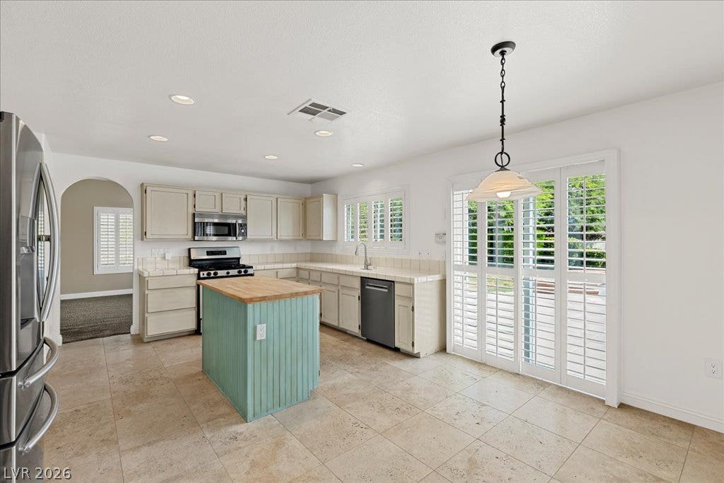 2000 Silverton Drive, Henderson, NV 89074 A cheerful kitchen featuring a unique turquoise island, ample counter space, and a bright patio access.