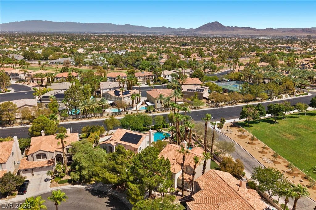 2000 Silverton Drive, Henderson, NV 89074 An aerial perspective reveals a vibrant neighborhood nestled among mountains, with numerous properties featuring pools and solar panels.