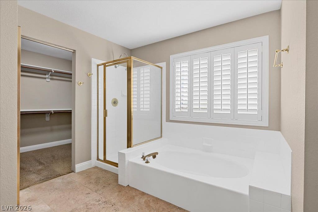 2000 Silverton Drive, Henderson, NV 89074 An inviting primary bathroom features a corner tub, a glass-enclosed shower, and a practical walk-in closet.