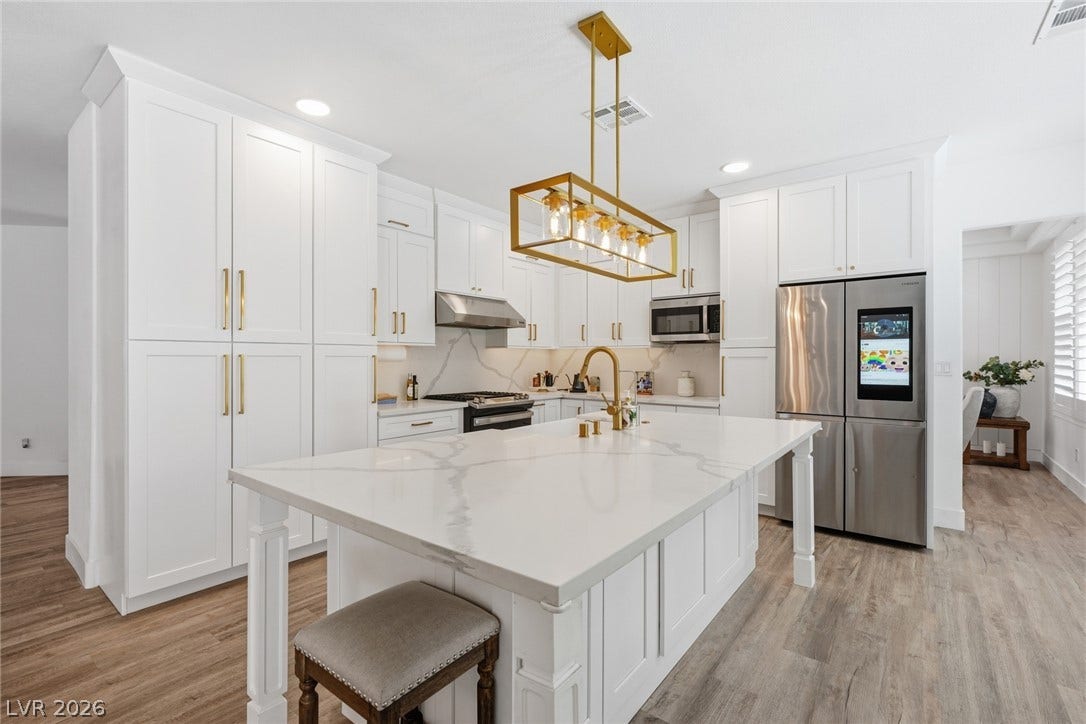 9615 Sedona Hills Court, Las Vegas, NV 89147 A well-lit culinary space features abundant white cabinetry, a spacious island, and modern stainless steel appliances.