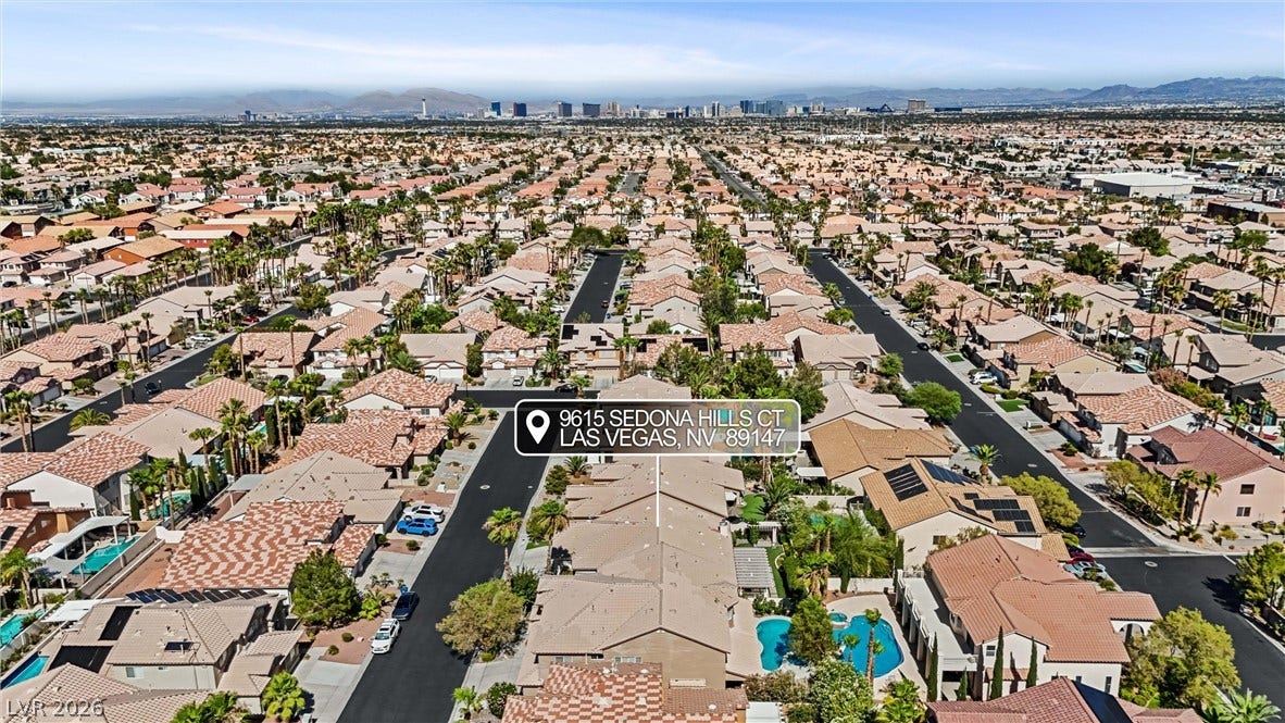 9615 Sedona Hills Court, Las Vegas, NV 89147 An aerial panorama showcases a vibrant neighborhood of homes with desert landscaping and private pools, set against a distant cityscape.