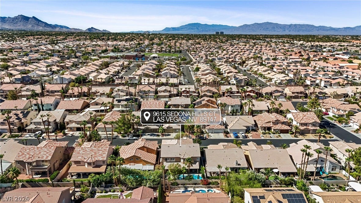9615 Sedona Hills Court, Las Vegas, NV 89147 An aerial perspective reveals a vast suburban neighborhood set against a distant mountain range.