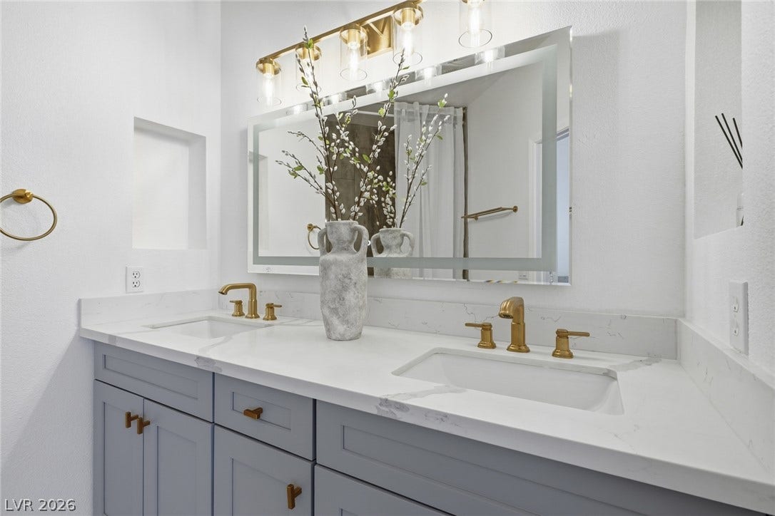 9615 Sedona Hills Court, Las Vegas, NV 89147 Double vanity with sleek white countertops and modern brass fixtures defines this bathroom's sophisticated appeal.