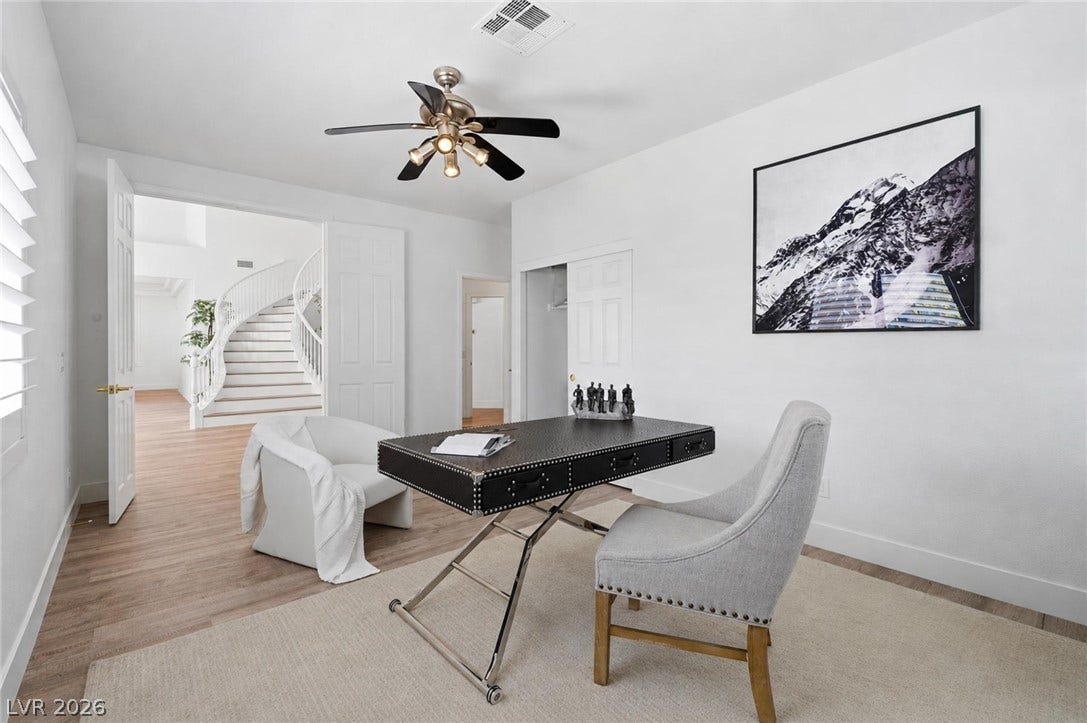 9615 Sedona Hills Court, Las Vegas, NV 89147 An inviting study offers a quiet retreat with a functional desk and a graceful, curving staircase visible beyond.