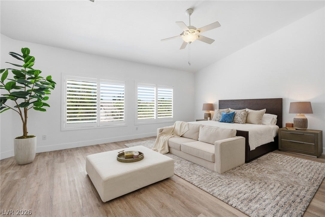 9615 Sedona Hills Court, Las Vegas, NV 89147 A generously sized sleeping quarter features hardwood floors and a ceiling fan, with natural light filtering through the windows.