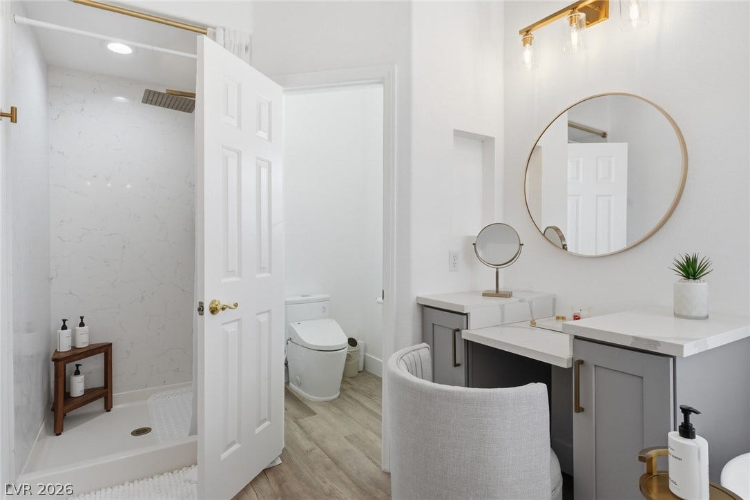 9615 Sedona Hills Court, Las Vegas, NV 89147 A well-appointed bathroom features a modern shower, wood-look flooring, and a functional vanity with elegant gold fixtures.