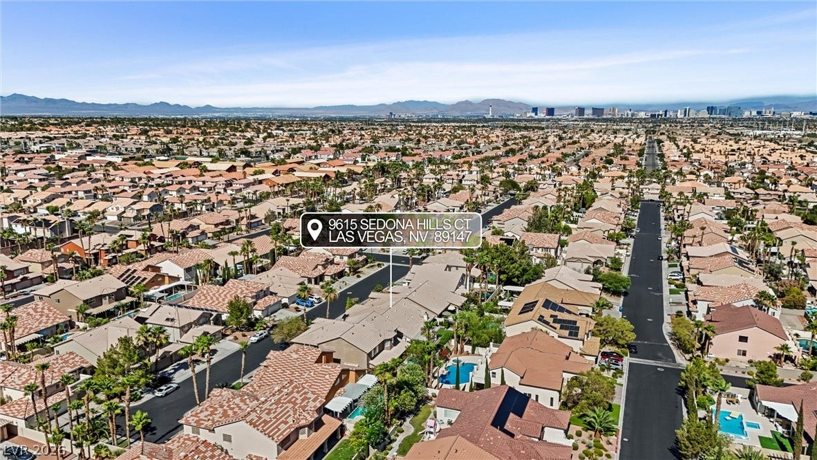 9615 Sedona Hills Court, Las Vegas, NV 89147 An aerial perspective showcases a vibrant neighborhood with diverse rooftops and distant mountain views.