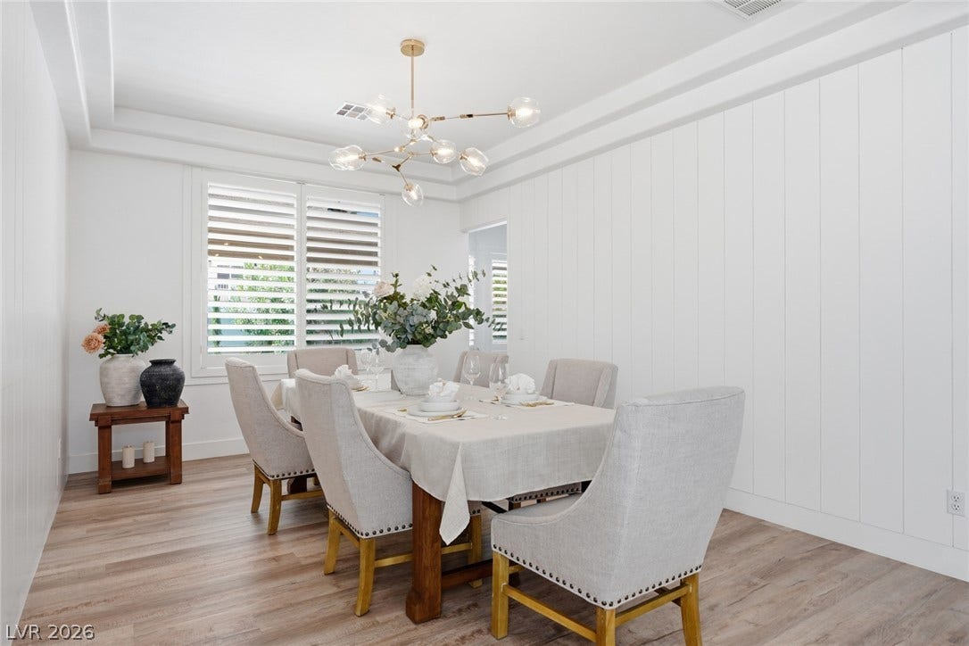 9615 Sedona Hills Court, Las Vegas, NV 89147 A graceful dining area, well-lit by natural illumination, featuring light wood flooring and a distinctive ceiling fixture.