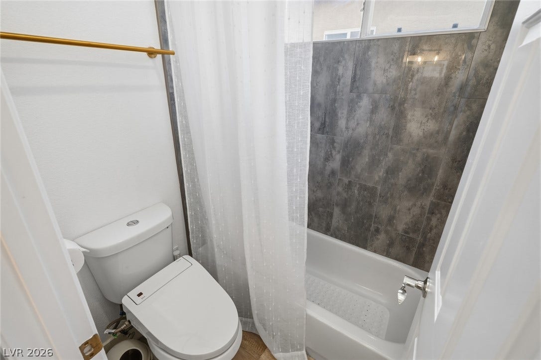 9615 Sedona Hills Court, Las Vegas, NV 89147 A well-appointed bathroom features a modern toilet and a tiled shower-tub combination, blending functionality with clean design.