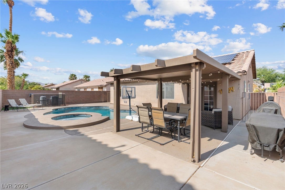 A private backyard oasis features a shimmering pool, spa, and shaded patio for outdoor entertaining.