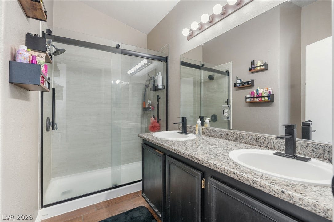 Double vanities and a modern glass-enclosed shower complete this well-appointed bathroom.