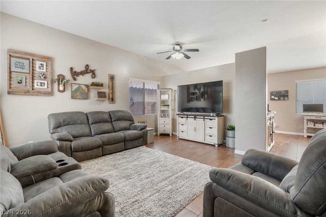 A comfortable living space boasts durable wood flooring and a refreshing ceiling fan.
