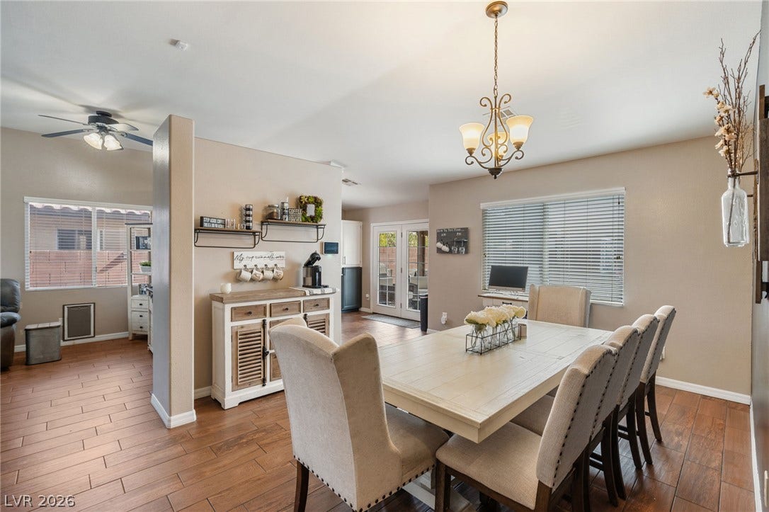 An inviting dining area features elegant wood flooring, a decorative chandelier, and French doors leading to an outdoor space.