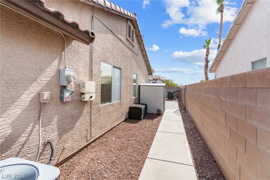 A convenient side yard features a paved walkway, practical storage shed, and secure block wall fencing.