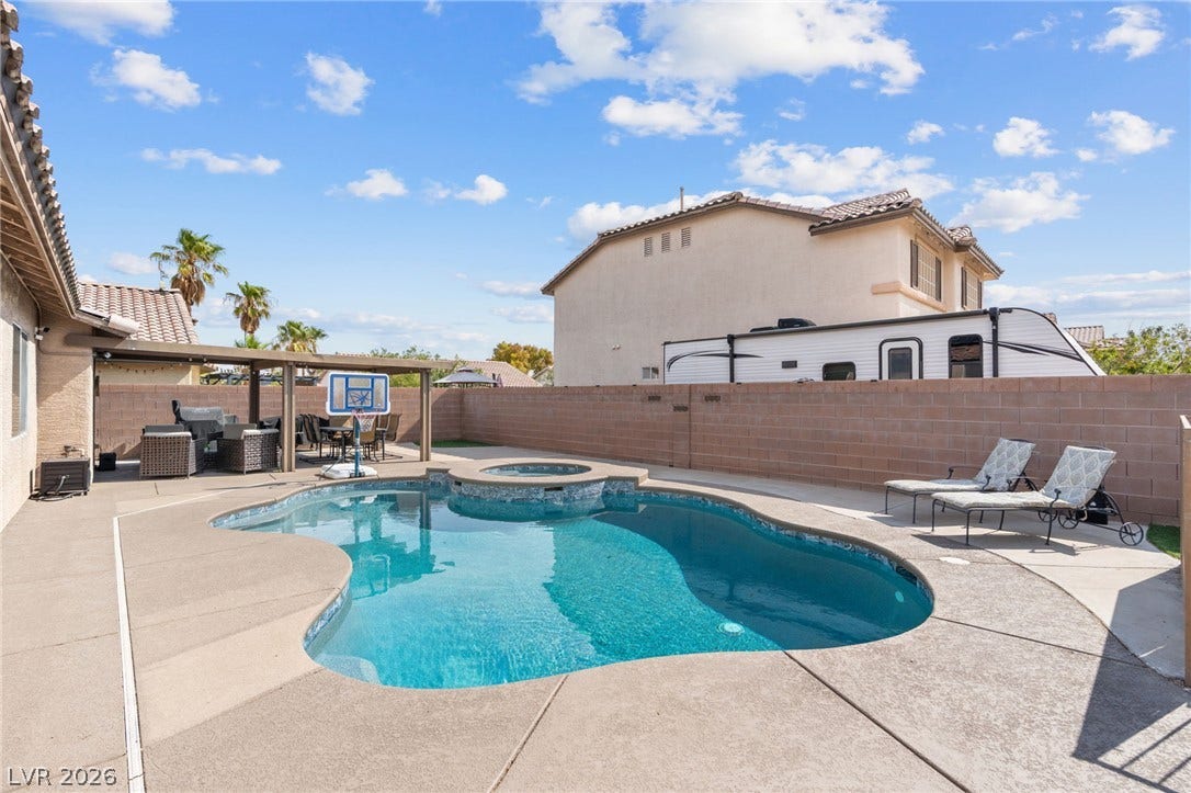 An inviting backyard oasis offers a freeform pool and a covered patio for ultimate outdoor living.