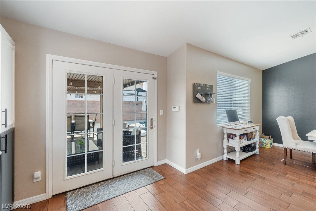 Hardwood floors lead to a sun-drenched patio through elegant French doors, offering seamless indoor-outdoor living.