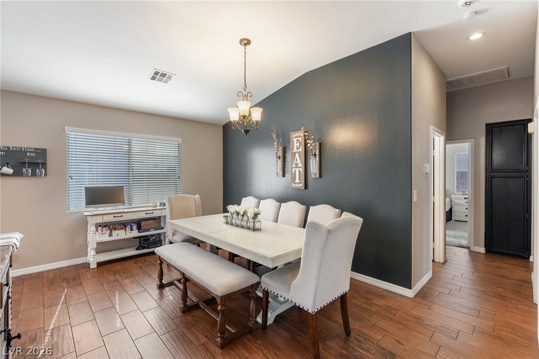 Hardwood flooring flows through this welcoming dining area, illuminated by a classic chandelier.