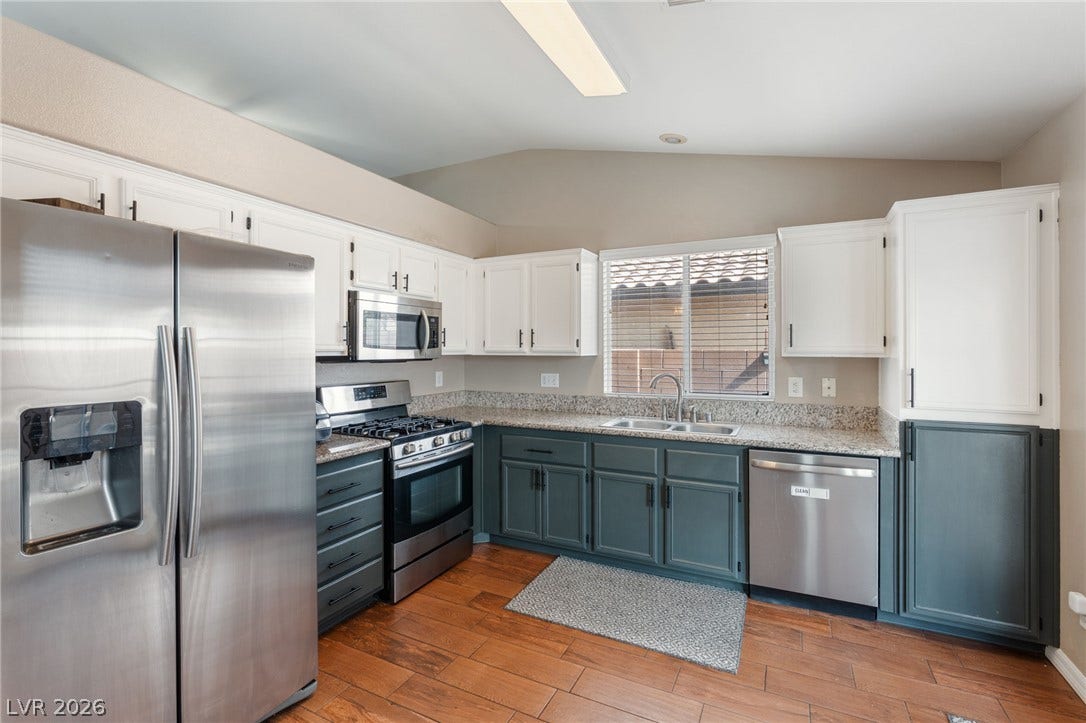 A well-appointed kitchen features rich wood flooring and gleaming stainless steel appliances.