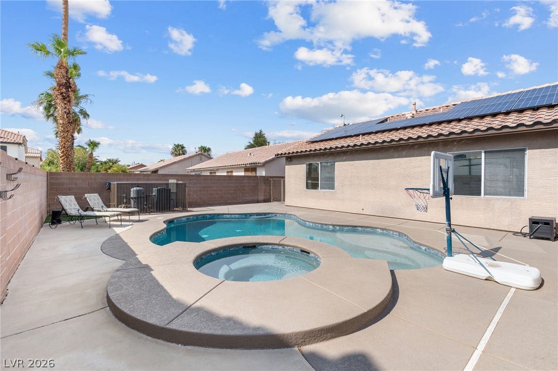 An inviting backyard oasis offers a free-form pool with an integrated spa, perfect for relaxation or recreation.