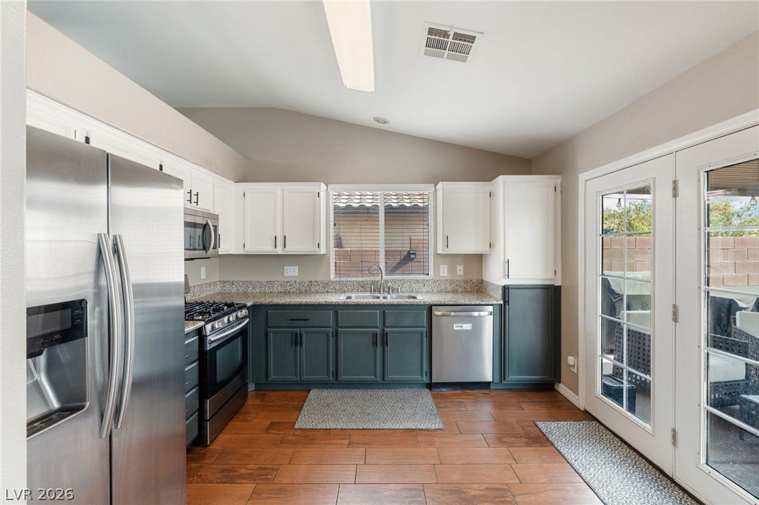 A well-appointed kitchen features stainless steel appliances, ample cabinetry, and rich wood flooring.