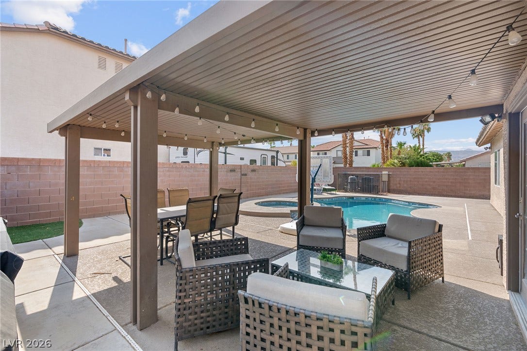 An inviting outdoor living area features a covered patio, perfect for enjoying the sparkling pool and relaxing spa.