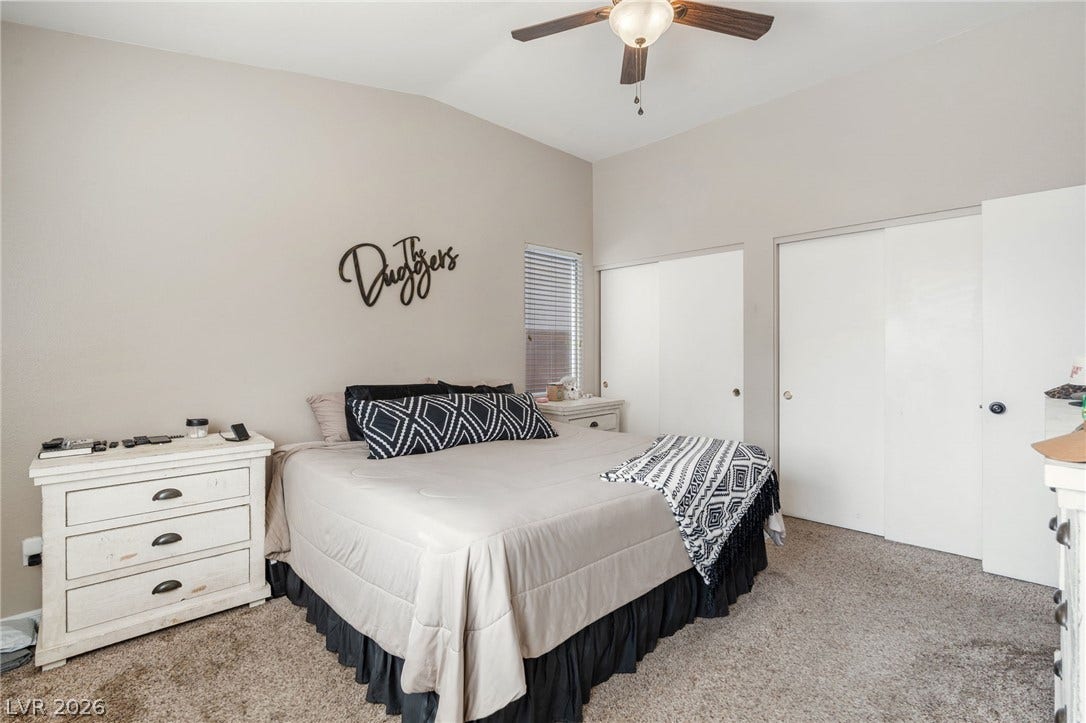 A well-lit bedroom features vaulted ceilings and ample storage.