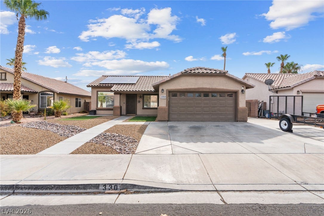 A desert-friendly landscape surrounds this charming stucco home with an attached garage.