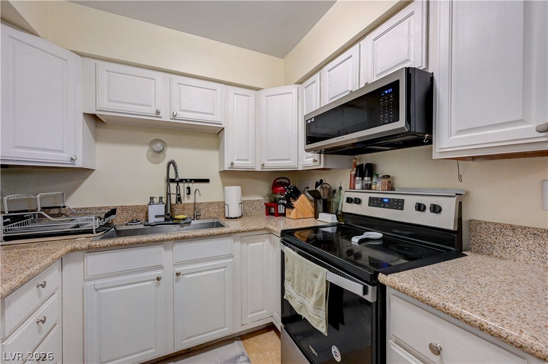 263 E Van Wagenen Street, Henderson, NV 89015 Gleaming stone countertops and classic white cabinetry define this functional, well-appointed kitchen layout.
