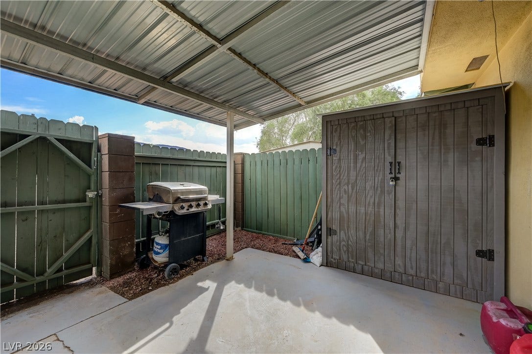 263 E Van Wagenen Street, Henderson, NV 89015 A covered concrete patio provides sheltered outdoor space enclosed by a sturdy wooden privacy fence.