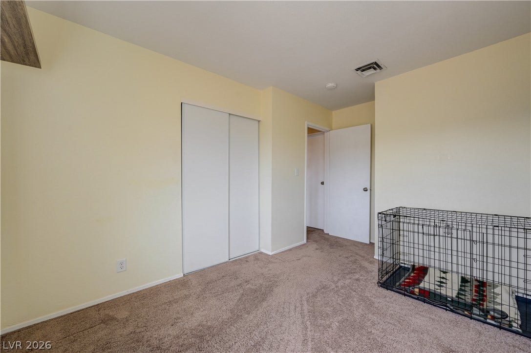 263 E Van Wagenen Street, Henderson, NV 89015 A spacious bedroom featuring soft wall tones, wall-to-wall carpeting, and sliding closet doors.