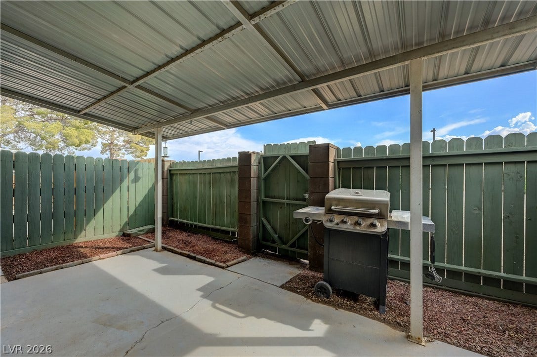 263 E Van Wagenen Street, Henderson, NV 89015 A covered concrete patio provides sheltered outdoor space bordered by sturdy wooden fencing.