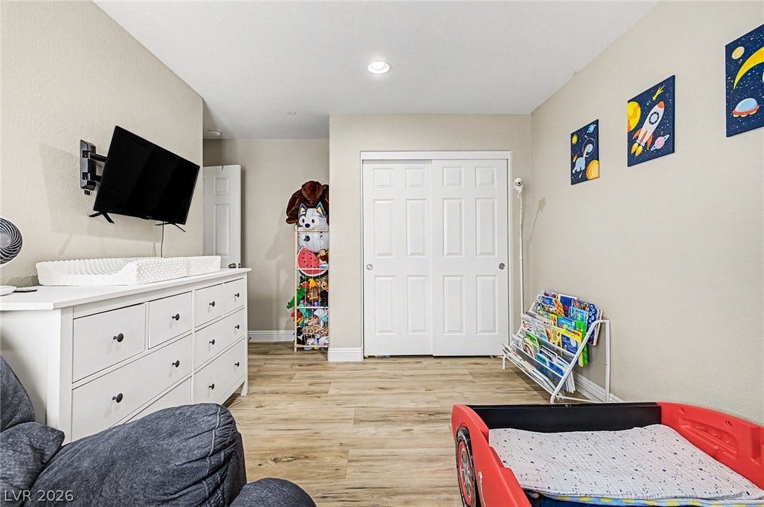 Hardwood-style flooring extends across this naturally illuminated bedroom with a practical closet.