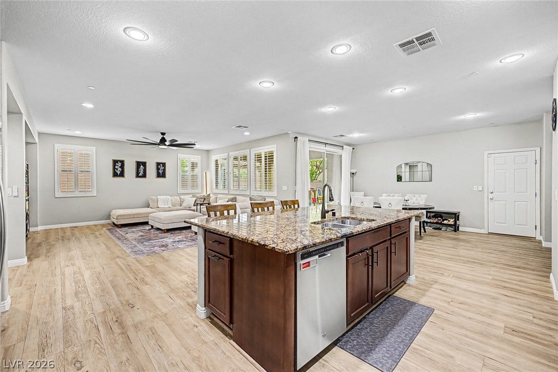 An open concept living area features a kitchen island with seating, seamlessly connecting to the living and dining spaces.