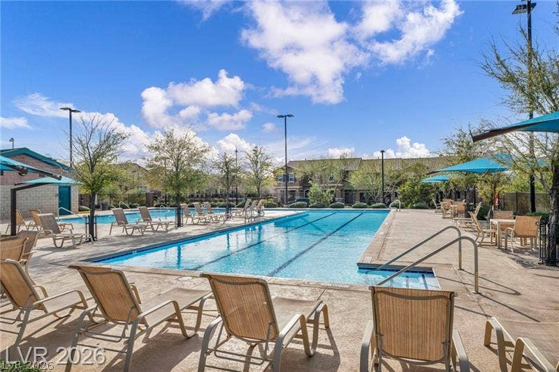 An inviting lap pool with a concrete deck under blue skies.
