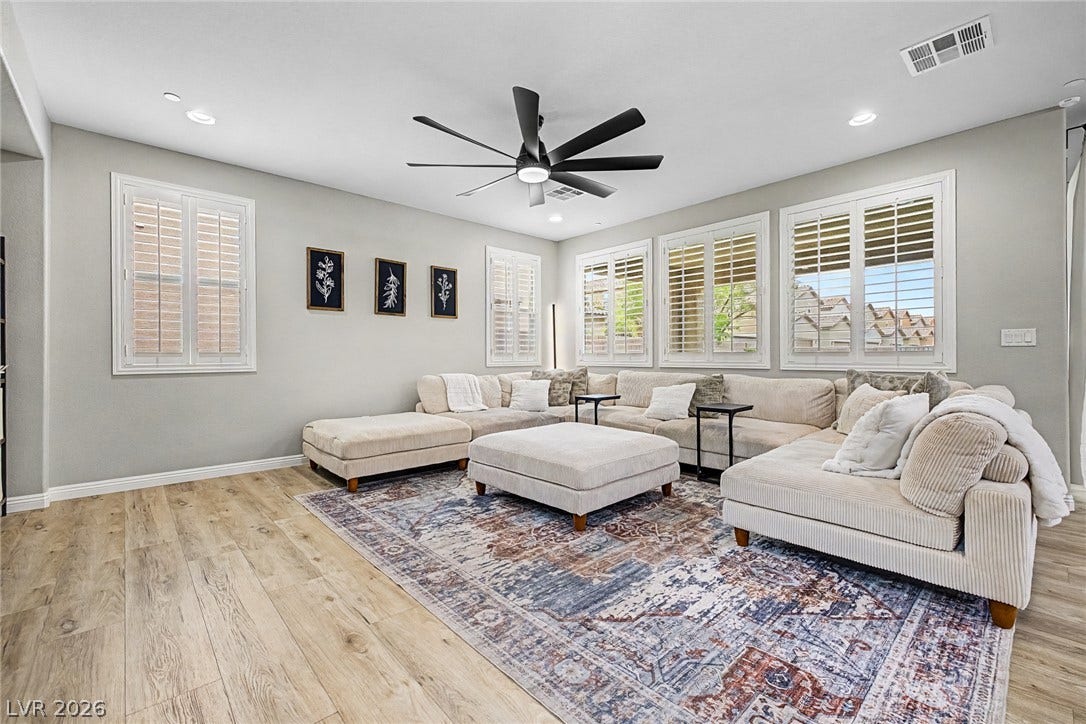 A naturally illuminated living room featuring rich wood flooring and elegant window shutters.