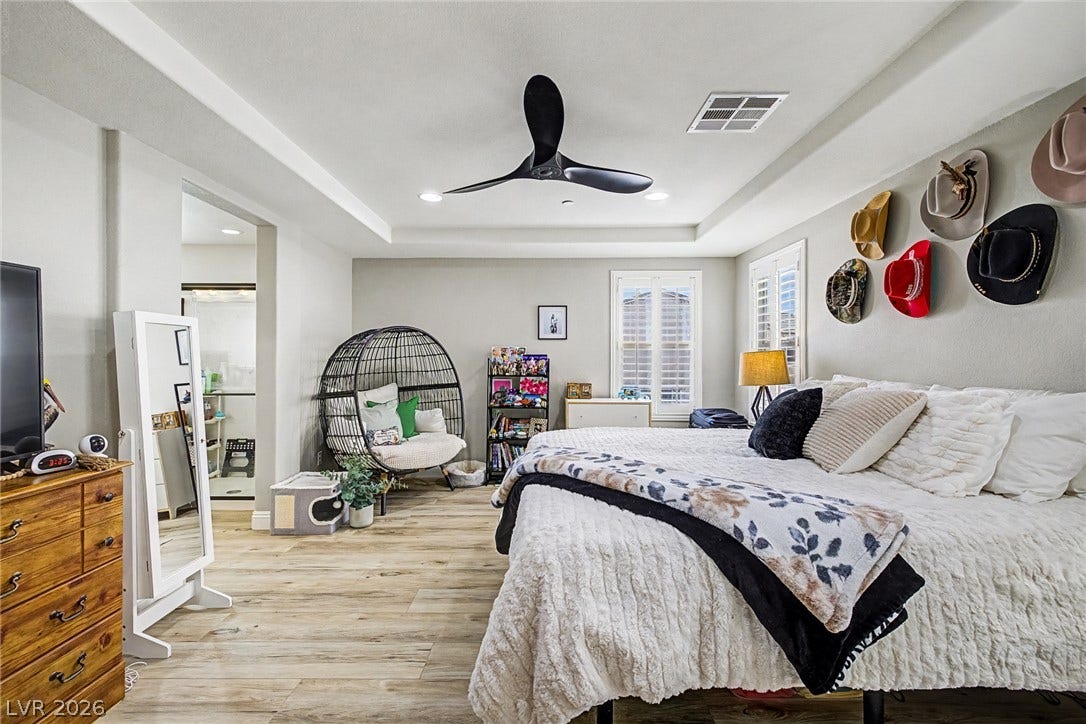 Recessed lighting and a modern ceiling fan illuminate this comfortable bedroom featuring rich wood flooring and elegant window shutters.