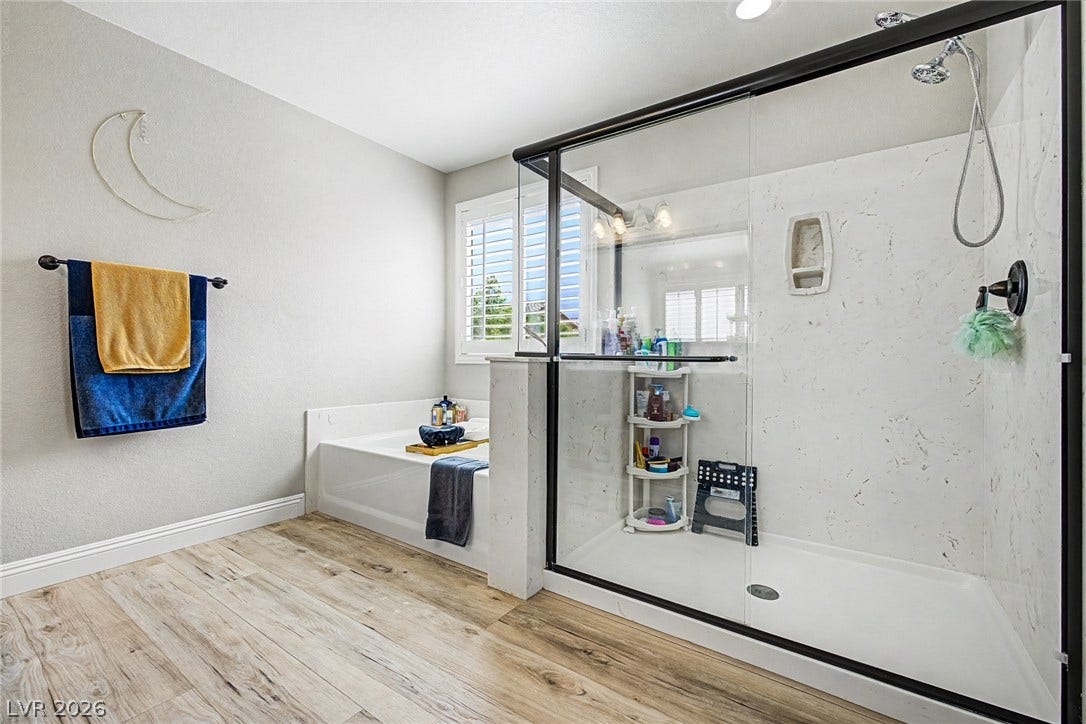 A well-appointed bath features a deep soaking tub and a spacious, clear glass shower.