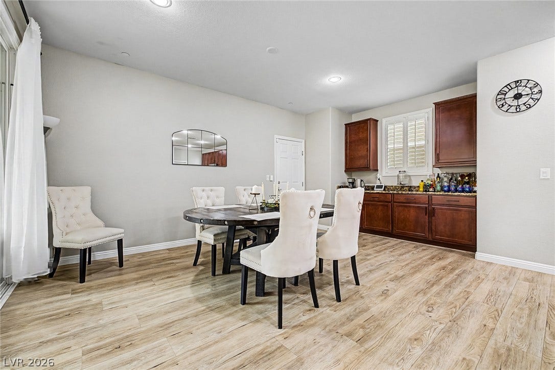 Blonde wood flooring and recessed lighting illuminate this open-concept dining space, complemented by rich cabinetry and granite counters.